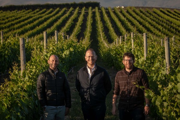 Railsback & Freres standing in the vineyard with the sunset behind them.